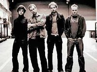 Coldplay  Posed shot of the band in a parking lot. Guy Berryman is wearing a pair of Chuck Taylors.